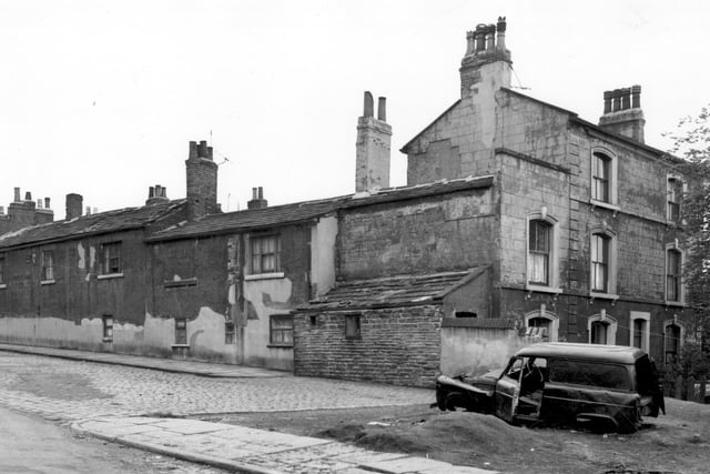On the left of this view, the backs of houses on Barnet Square can be seen. View looks from Strawberry Road. On the right edge is number 12 Barnet Mount, an old building which had originally been known as Southfield House. Occupants of this house in 1861 were trading as Brown and Rhodes Brothers. In the foreground an abandoned car can be seen.