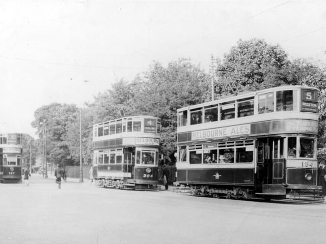 Three trams at the Roundhay Park tram stop on Princes Avenue in July 1934. The tram in the distance to the left is number 147. In the centre, tram number 394 is on route 4 with the destination shown as Kirkstall Abbey. Tram number 154 is to the right, this tram is travelling to Beeston on route 5 via Beeston Road. Trams are decorated with adverts for Melbourne Ales.