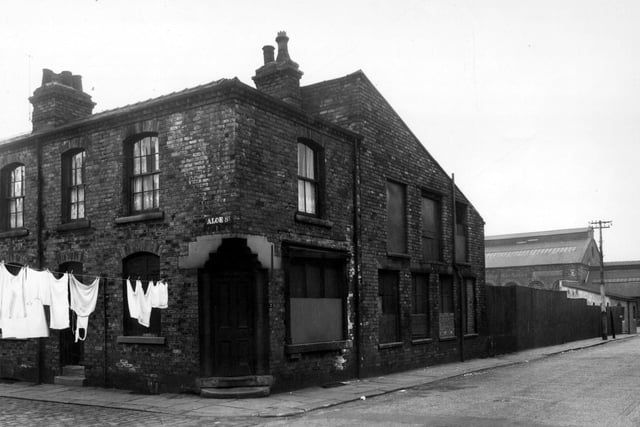 Aloe Street runs from the left of this view. Holm Street is on the corner with a shop window and a carved stone door lintel. Holm Street continues to the right edge where an iron and aluminium foundry on Sayner Lane can be seen.