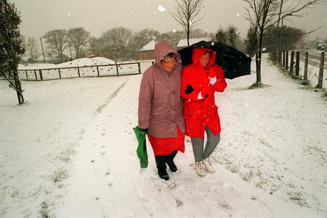 Brenda Teet and Gillian Lewyckyj  battle through the snow on their way to work at Drighlington Primary School in  November 1996.