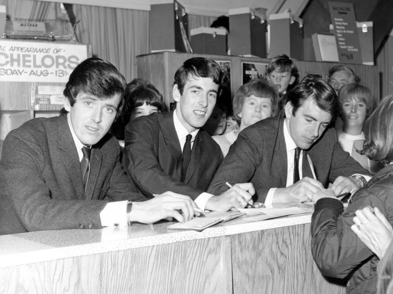 Pop group The Bachelors on a visit to the new Vallances store on New Market Street in August 1964. They flew into Leeds Bradford Airport from Blackpool where they had been performing for the summer season on the Central Pier. A crowd of several hundred fans came to see them on their visit to Leeds and there were four police constables on duty. The Bachelors are seen here signing autographs and copies of their latest record. In 1964 the Bachelors released the singles, Diane, Ramona, I believe, I Wouldn't Trade You For The World and No Arms Could Ever Hold You. They also released two EPs and an album in the same year.