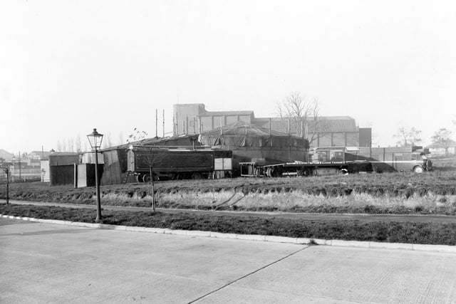 A section of the ring road pictured in October 1941. In the background is a fairground roundabout covered in tarpaulin. A caravan is parked next to it. The fair is on the site of the current Red Lion public house, formerly known as the Traveller's Rest. Soon after the Second World War the land housed a day nursery, prior to the building of the Traveller's Rest. The building at the back is the Regal Cinema, which opened in November 1936 and closed in January 1964.