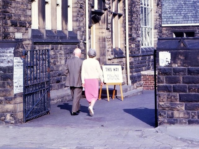 Using the schools for voting at local council elections in Morley. Here this couple are going to vote at Cross Hall Junior School, Fountain Street, which was a polling station for the Dartmouth ward. Pictured in May 1965.