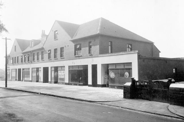 Row of shops mainly empty on Kirkstall Hill. To the front of photo is the gate to a residential property bearing the word 'Glendale'. A workman stands in the doorway to the end shop. Cliff Coldwell house furnishers is at 152 and appears to have living accommodation above Jubilee Fisheries and Thrift stores can be seen. Pictured in August 1935.