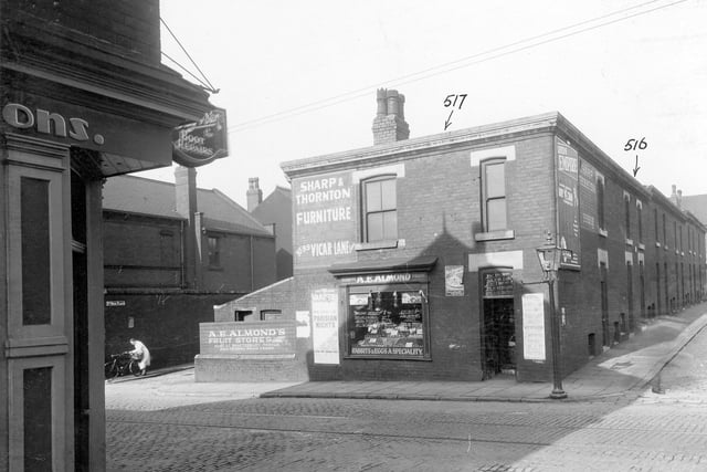 The junction of Stoney Rock Lane and Rock View Road. At the end of the terrace houses on Rock View Road is situated the premises of Albert Edwards Almond, greengrocers. A street lamp is directly outside the shop. A painted hoarding advertises Sharp and Thornton furniture store and there is also a poster for the City Varieties on the wall. Pictured in September 1935.