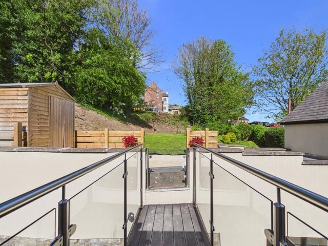 A wooden bridge and glass balcony leads from the landing out to the beautifully landscaped rear garden.