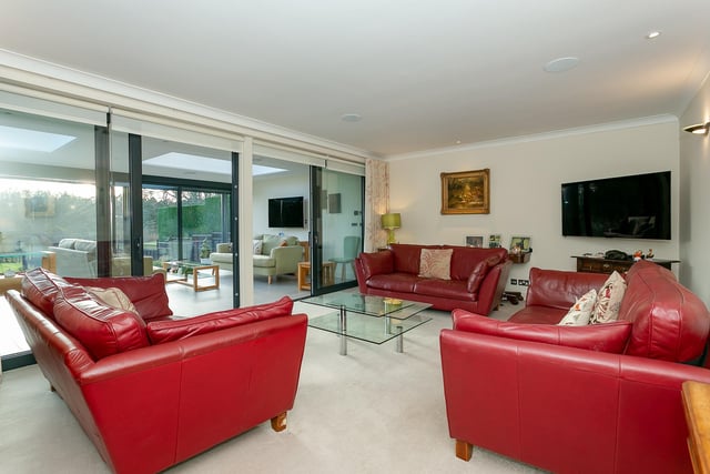 A sitting room extends through sliding glass doors to a garden room with heated tiled floor.