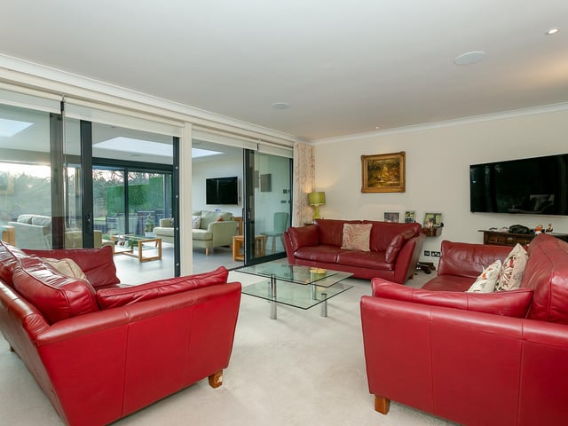 A sitting room extends through sliding glass doors to a garden room with heated tiled floor.
