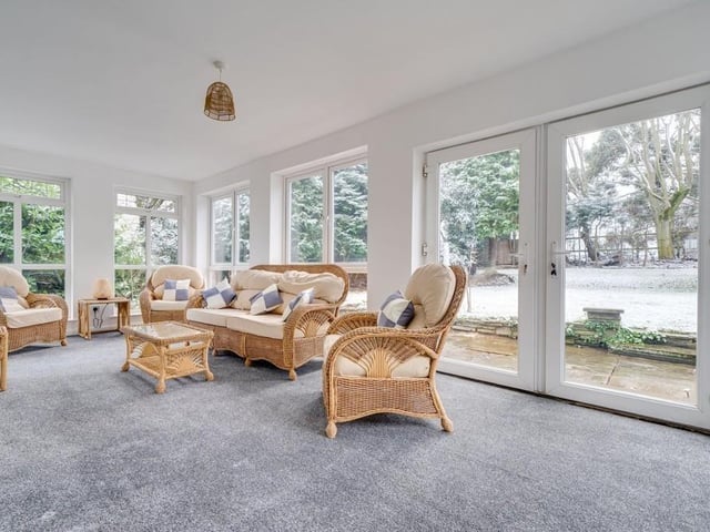 The conservatory or sun room looks out over the garden, with doors to a patio area.