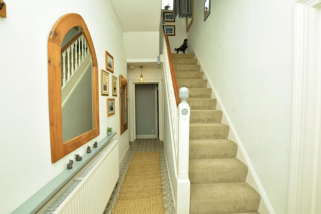 The staircase rises from the L-shaped hallway within the house.