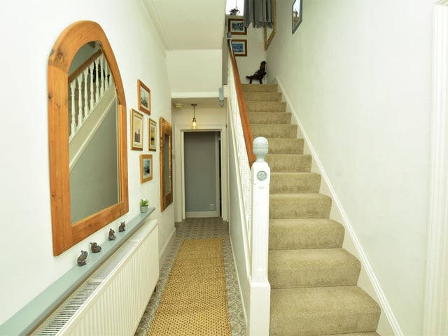 The staircase rises from the L-shaped hallway within the house.
