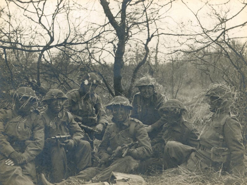 A black and white photograph of Leeds Home Guard in Training entitled 'Our Demonstration Team' (soldiers in camouflage). This group are equipped with Sten submachine guns, which were issued to the home guard as they became available around 1942. Leeds Sub-area School of Tactics taught hundreds of officers and senior NCOs in Golden Acre Park. (Yorkshire Post & Leeds Intelligencer 1/11/44). In his account of the 9th Battalion written in September 1945, Commanding officer Lt Col HK Boyle DSO writes about these weekend schools where Tactics, Weapon Training, Bombing, Intelligence, Gas, Street Fighting, Umpiring, Ammunition, Catering, Hygiene and Civil Defence were taught - 'Three very full and concentrated week-ends on top of a full time civilian job, though, proved very gruelling to most of those who undertook this'.