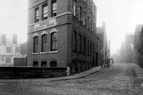The Queens Lodging House on Garden Street pictured in September 1910. Improvements can be seen on East Street to the right side of the picture. To the left is a shed with 'John Pickard, Builder', written on the side. Two men are visible in the distance carrying an object on East Street.