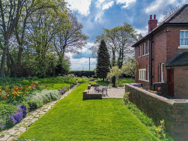To the front of the property is an expansive lawned garden with a feature pond and planted border incorporating mature trees, shrubs and flowers surrounded by walls and hedging. There is also a stone paved patio area, perfect for outdoor dining and entertaining.