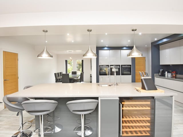 A breakfast bar forms part of the kitchen island, with the family dining area beyond.
