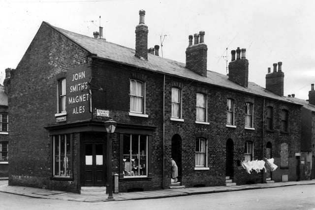 The junction of Bewerley Street with Cross Alpha Street. The shop on the corner is number 35 Bewerley Street and numbers ascend to the right. Number 41 on the right has been vacated and a door and ground floor window have been bricked up. A woman enters number 37. Pictured in June 1964.