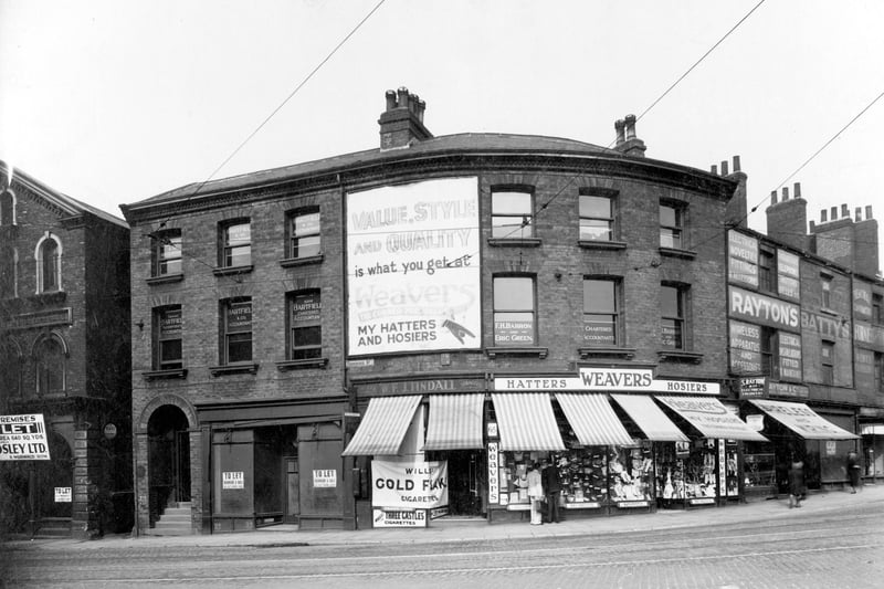 The junction of Cookridge Street amd Woodhouse Lane in May 1936. A large poster on the wall in the centre advertising Weavers shirt shop, at no.65 Woodhouse Lane. Business of Alfred Weaver, display of goods in windows.