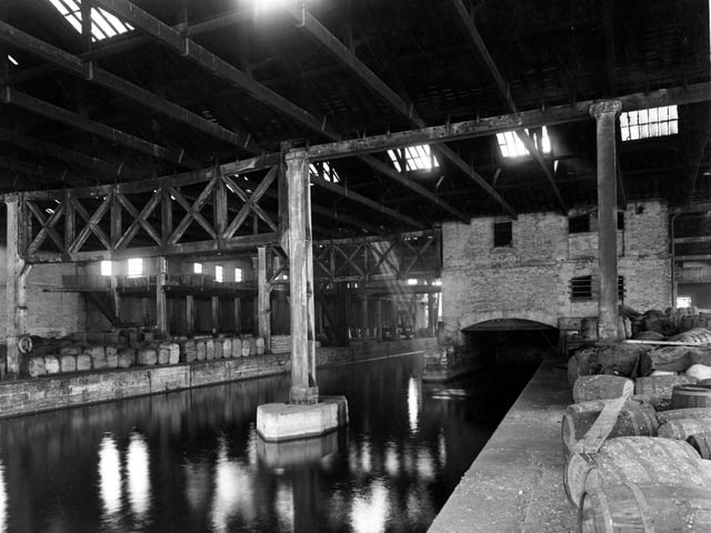 A view of warehouse belonging to British Waterways on Dock Street showing canal running through large building. On the dockside are lots of packing cases, bales and barrels. Pictured in September 1950.