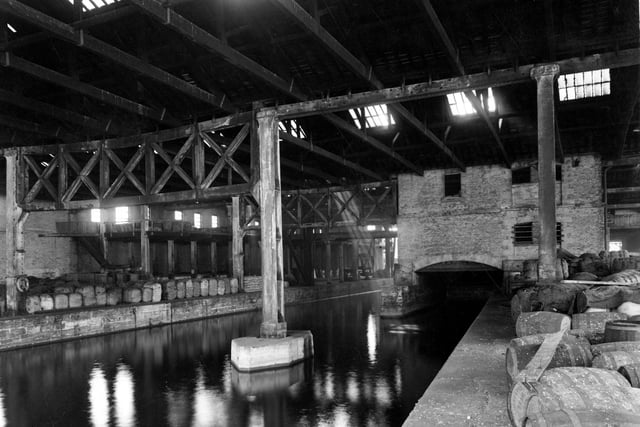 A view of warehouse belonging to British Waterways on Dock Street showing canal running through large building. On the dockside are lots of packing cases, bales and barrels. Pictured in September 1950.