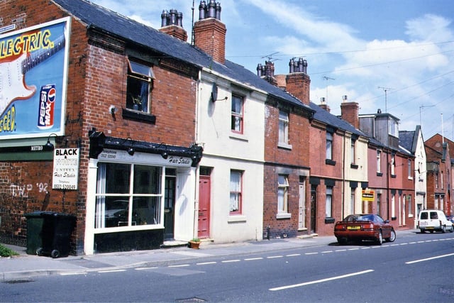 Station Road, one of the few rows of "tunnel back housing" in Morley, though from this front view they look no different to any other row of terraced housing. On the left is the Black & White Hair Studio, which has an advertising hoarding for Pepsi Max on its gable end. Pictured in July 1994.