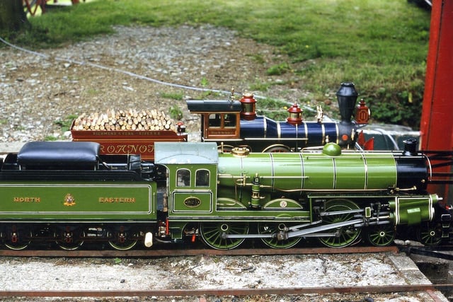 Two steam locomotives. In the background is a locomotive based on an engine from the Richmond and York River Railroad. The railroad played a key part in the Peninsula Campaign of the American Civil War in 1862. This miniature engine is built to 7.25 gauge by Roanoke near Barnstaple. The green engine is a miniature version of the first North Eastern Railways Uniflow locomotive, number 825. It was adapted in 1913 by Sir Vincent Raven from an S-class 4-6-0 mixed traffic locomotive (no. 825). It is possible to see the two uniflow cylinders mounted at an angle, side front.