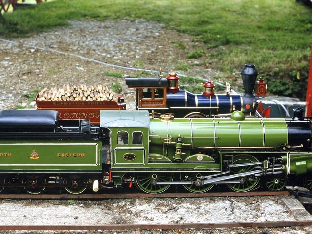 Two steam locomotives. In the background is a locomotive based on an engine from the Richmond and York River Railroad. The railroad played a key part in the Peninsula Campaign of the American Civil War in 1862. This miniature engine is built to 7.25 gauge by Roanoke near Barnstaple. The green engine is a miniature version of the first North Eastern Railways Uniflow locomotive, number 825. It was adapted in 1913 by Sir Vincent Raven from an S-class 4-6-0 mixed traffic locomotive (no. 825). It is possible to see the two uniflow cylinders mounted at an angle, side front.