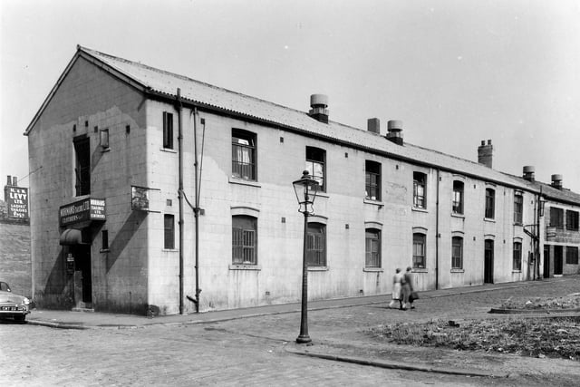 On the left of the image is Firth Street and the entrance to number 8 a clothing works listed as the premises of H & H Levy Ltd Ladies Tailors and Normans (Tailors) Ltd, Clothiers. On the right can be seen the side of the works on Pilot Street with another clothing works visible on the far right. This area was locally known as Newtown. Pictured in September 1959.