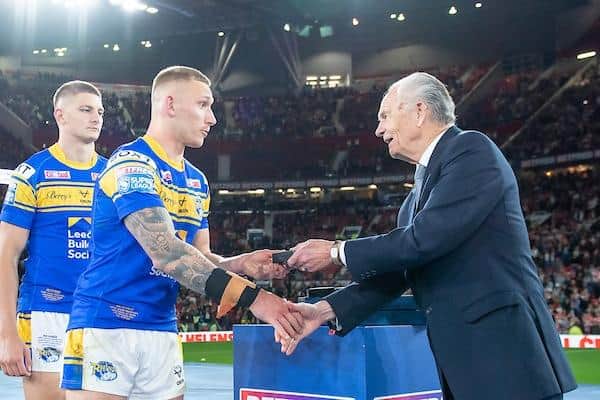 Sam Walters, left, waits as Rhinos teammate Mikolaj Oledzki receives his Grand Final runners-up medal from Super League chairman Ken Davy. Picture by Allan McKenzie/SWpix.com.