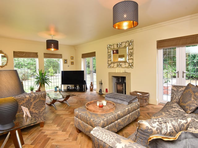 This stylish sitting room has parquet flooring, with a feature fireplace and wood-burning stove. Patio doors lead outside.