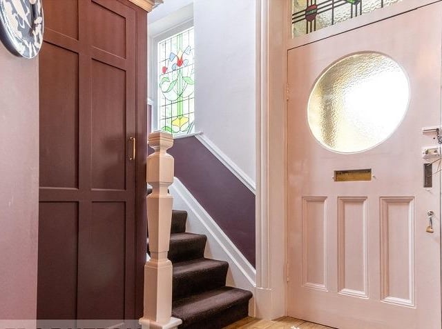 A hallway with staircase leading up, leads in to the property.