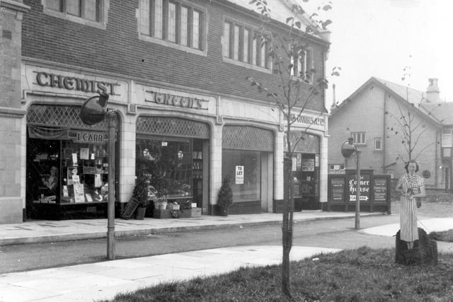 A view of Corner House shops from Street Lane in September 1936. On the left no8 Lewis Carr chemist, next no9 Greens selling fruit and flowers No 10 is empty. Last no11. James Coombes and co, shoe repairs,. On the right a cardboard cut-out of a woman probably advertising film sold at the chemists.