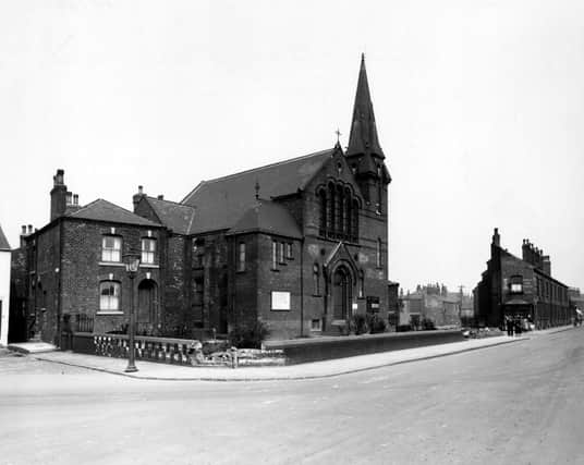Hunslet Carr Methodist church on Moor Road with two sections of the wall collapsed. A streetlamp is in the foreground and an advertisement for Capstan tobacco can be seen on the gable end of a building in the background. People are walking along the street. Pictured in April 1948.