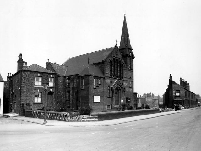 Hunslet Carr Methodist church on Moor Road with two sections of the wall collapsed. A streetlamp is in the foreground and an advertisement for Capstan tobacco can be seen on the gable end of a building in the background. People are walking along the street. Pictured in April 1948.