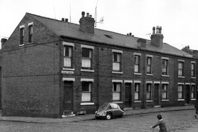 This view looks from Barnet Road onto four back-to-back houses on Barnet Terrace. Numbers run from 1 to 7 left to right. A Heinkel/Trojan Bubble car is parked outside number 1. A boy rides a tricycle along the sett-paved road. Pictured in May 1965.