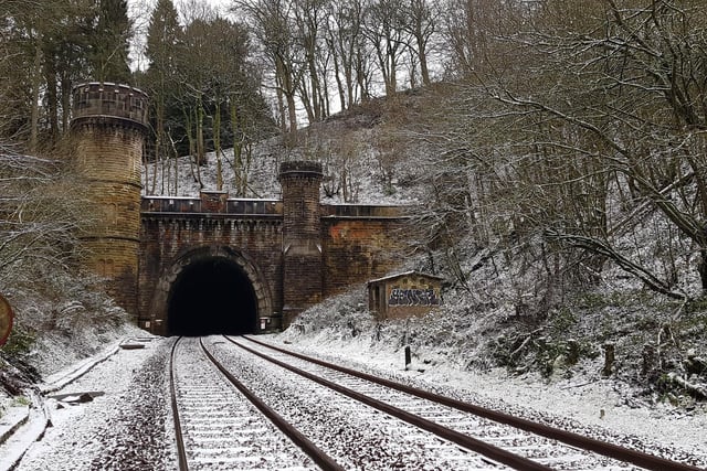 The North Portal of Bramhope Tunnel, looking south along the tracks, and showing the Grade II listed crenelated structure and the large and small towers. Carvings in the stone can be seen on and above the archway. The North Portal is located in Long Balk Wood, to the north of Bramhope village.