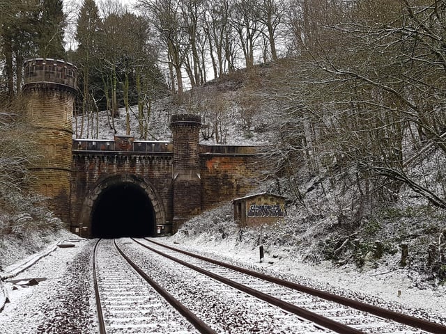 The North Portal of Bramhope Tunnel, looking south along the tracks, and showing the Grade II listed crenelated structure and the large and small towers. Carvings in the stone can be seen on and above the archway. The North Portal is located in Long Balk Wood, to the north of Bramhope village.