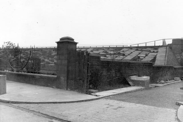 The corner of Church Lane and Kirkgate in April 1938, showing new paving stones. Railway embankment in the background is covered with gravestones.