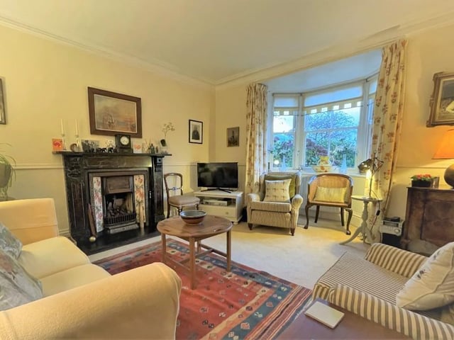 The sitting room, with a large front bay window, displays an original cast iron fireplace with tiled hearth.
