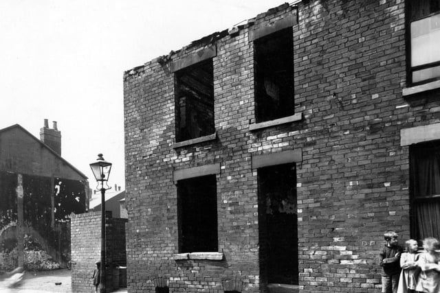 Three children lean against a wall of a derelict back-to-back house on Metcalf Street in July 1947. It backed onto number 34 Thornton Street.