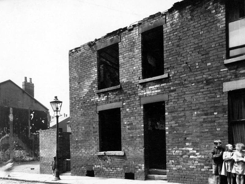 Three children lean against a wall of a derelict back-to-back house on Metcalf Street in July 1947. It backed onto number 34 Thornton Street.