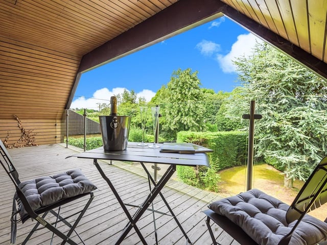 Covered decking with glass balustrade overlooking the garden.