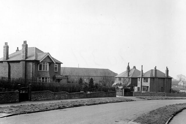 Sandhill Oval showing detached and semi-detached houses with gardens in March 1951. In the background is a long building which may be a factory. The long building in the background is the back of Sandhill Parade shops which face onto the Harrogate Road.