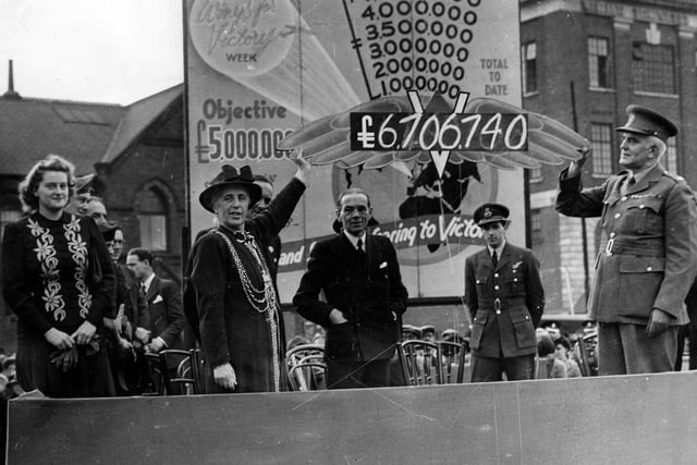 This is the culmination of Wings For Victory Week. At 7pm the final total of funds raised is held aloft by Jessie B. Kitson, Lord Mayor of Leeds and on the right Major J. Milner. The objective had been to raise £5 million, the total displayed was £6,706,740. The eventual sum was finally £7.2 million. The location was an exhibition ground created on a British Legion car park at the bottom of Eastgate. Pictured in Ju8ly 1943.