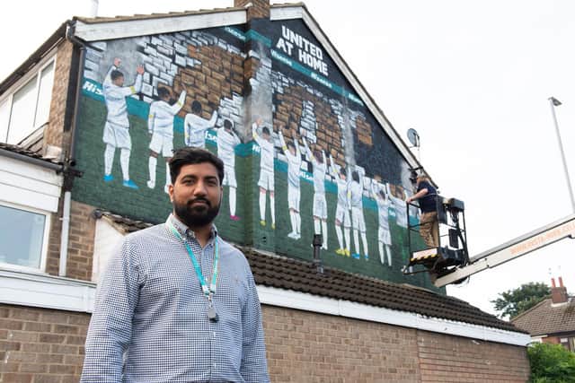 Hisense UK head of marketing Arun Bhatoye with their commissioned United at Home mural to welcome fans back to the ground
