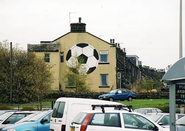 The unusually named Football, a street of very old stone built terraced properties, seen here from William Morrisons Supermarket car park situated in Harper Lane in October 2003. The gable end of number 2 boasts a huge black and white football painted and maintained by the current owners. It has become a famous landmark in the area. At one time the residents fought hard to retain the name of Football for their street when moves were afoot to rename it Northfield Terrace. The residents triumphed, however, and decorated Football with bunting in celebration. The land on which Football and the adjacent South View Terrace were built was thought to have been named Football fields.