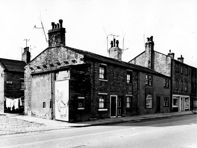 The junction of School Place on the left and Town Street on the right. On the far left the entrance to Mann's Square is visible where clothes hang on a line stretched across the street. At the corner is an advertisement for Batchelor's food products. On the right are numbers 11 to 17 Town Street, a row of back-to-back houses and through terraced shops. Pictured in September 1963.