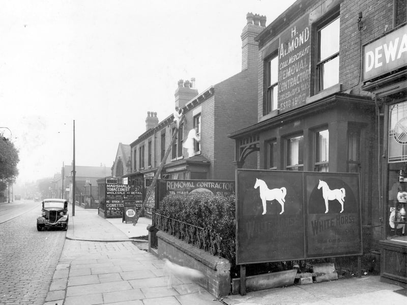 Dewsbury Road in June 1937. This small section of the road shows the premises of Marshall, Wholesale Tobacconist and H. Almond, Coal Merchant. A small portion of R. White, Wine and Spirit Merchants shop is visible.