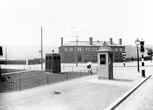 The junction of Meanwood Road and Stainbeck Road in June 1936  On the left, Buslingthorpe Rugby league ground is behind fence with Woodhouse Ridge in the background. Then the Meanwood Hotel, public house, landlord William Cardis. The road to the right of the Meanwood is Grove Lane, Stainbeck Road is in the bottom right corner. Street furniture includes a police box on the left, public telephone box, traffic lights and gas lamp.