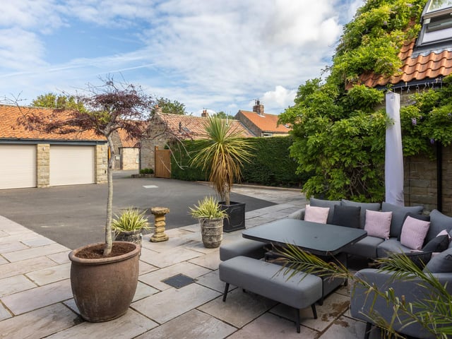 Sheltered seating to the front of the property, where there is also a double garage and parking space.