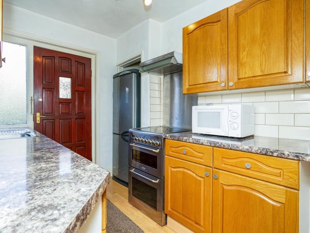 Upon entry, a hallway leads to a kitchen containing floor to ceiling units and a small utility cupboard.